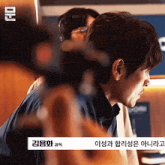 a man wearing headphones is standing in front of a camera with korean writing on the bottom right corner
