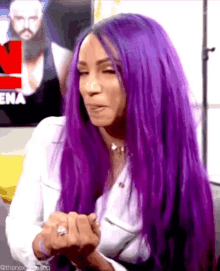 a woman with purple hair and a ring on her finger .