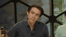 a man in a blue shirt is sitting in front of a sign that has the letter d on it