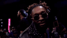 a man wearing sunglasses is standing in a wrestling ring with his mouth open .