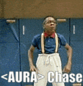 a man in a blue shirt and suspenders is standing in front of a blue wall with the words aura > chase written on it