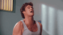 a man in a grey tank top is looking up at something