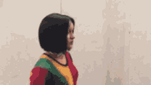 a woman with short black hair is wearing a multicolored shirt