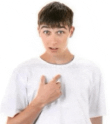 a young man in a white shirt is pointing at his chest