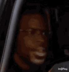 a man wearing glasses is sitting in a car and looking out the window .