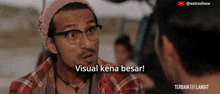 a man wearing glasses and a beanie talks to another man with the caption visual kena besar