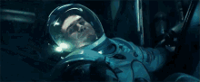 a man in an astronaut 's helmet is laying down in a space suit .