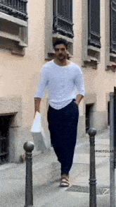a man is walking down the street holding a bag .