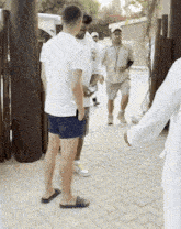 a group of men are standing on a brick sidewalk and talking to each other .