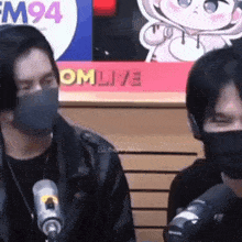two men wearing face masks are sitting in front of a sign that says omlive