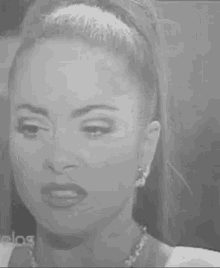 a black and white photo of a woman 's face with a serious look on her face .