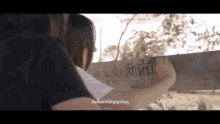 a woman is writing on a wooden board with a foreign language