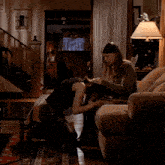 two women are kneeling down in a living room and one has her head on the other 's knee