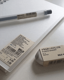 a muji plastic eraser sits next to a notebook