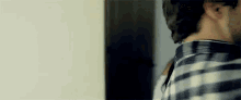 a man in a plaid shirt is standing next to a woman in a dark room .