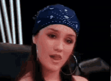 a woman wearing a blue bandana and hoop earrings is sitting in front of a microphone .