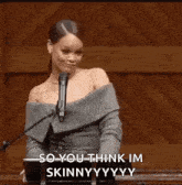 a woman is standing in front of a microphone and saying `` so you think im skinny . ''