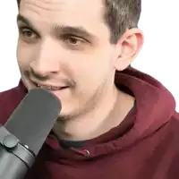a man in a maroon hoodie is speaking into a microphone