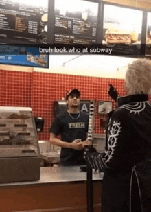a man wearing a shirt that says fresh stands at a counter