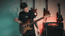 a man playing a guitar in front of a wall of guitars one of which says ' not like ' on it