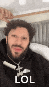 a man with curly hair and a beard is laying on a bed with a marker in his mouth .