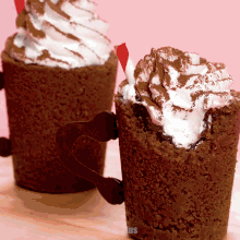 two brownie cups with whipped cream and cocoa powder