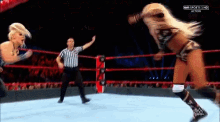 a female wrestler is jumping in the air while a referee looks on
