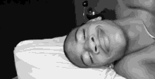 a man without a shirt is laying on a bed with his eyes closed .