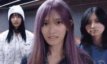 a girl with purple hair is standing next to two other girls .