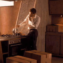 a man in a white shirt is standing in a kitchen talking on a cell phone next to boxes that say 11