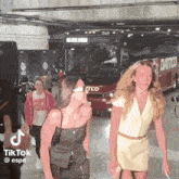 two women are standing next to each other in front of a bus that says daitto on it .