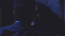 a man and woman are hugging in a dark bedroom