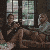 two women sit on a couch drinking wine