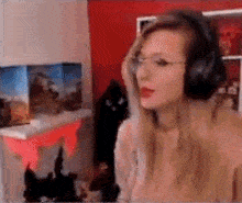 a woman wearing headphones and glasses is sitting in front of a computer monitor .