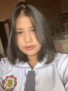 a girl wearing a white shirt with a red emblem that says " jatnao college "