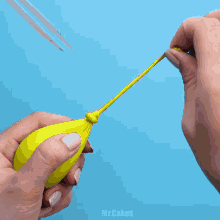 a woman 's hands are holding a yellow object on a blue surface ..