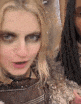 a woman with dreadlocks is standing next to another woman with blonde hair