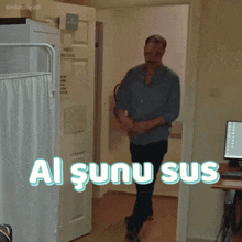a man in a blue shirt is standing in a room with the words " al şunu sus " above him