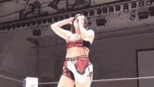a woman in a wrestling ring holds a microphone in her hand with the letter l on it