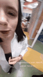 a woman in a white shirt is walking down a hallway with russian writing on the floor