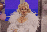 a drag queen is wearing a white feathered coat and a necklace
