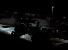 a woman in a green jacket sits in a dark area