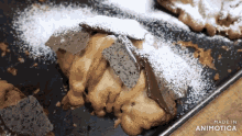 a close up of a pastry with powdered sugar on it and the words made in animotica on the bottom right