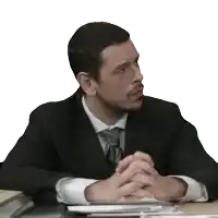 a man in a suit and tie sits with his hands folded