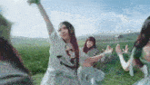 three women are dancing in a field with one wearing a shirt that says ' c7 '