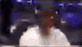a blurry picture of a man in a white shirt standing in front of a blue background .