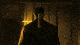 a man is standing in a dark room holding a sword in his hand .