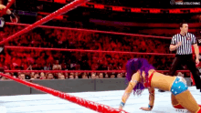 a woman in a wonder woman outfit is kneeling down in a wrestling ring .