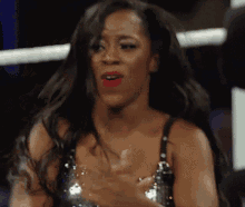 a woman in a sequined top is clapping her hands in a wrestling ring