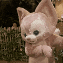 a stuffed animal is standing in front of a fence and looking at the camera .